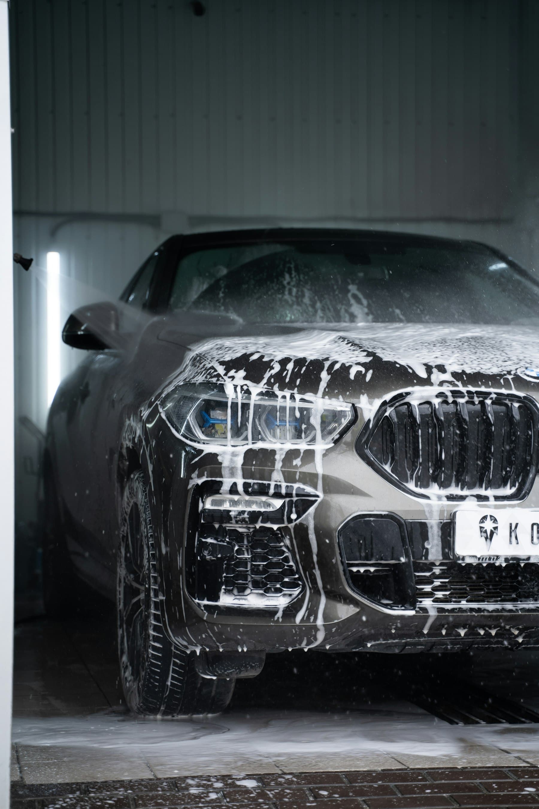 A car covered in snow foam in a detailing bay